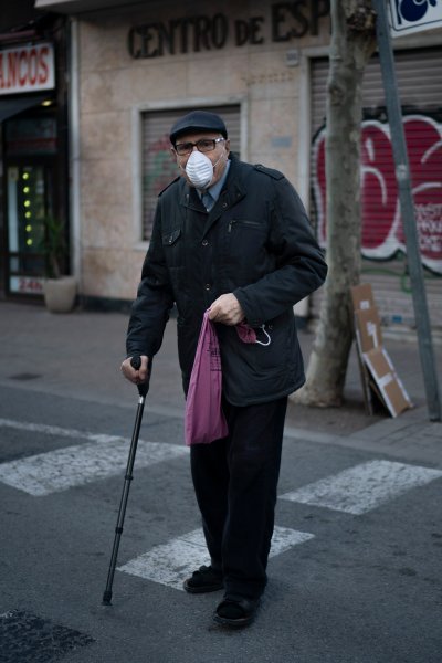 An elderly man wearing a face mask walks home from the bakery as the lockdown to combat the spread of coronavirus continues in Badalona, Spain, Friday, March 27, 2020. The new coronavirus causes mild or moderate symptoms for most people, but for some, especially older adults and people with existing health problems, it can cause more severe illness or death.