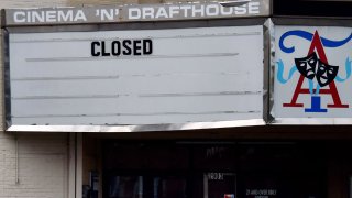 A woman wearing a face mask walks past the closed Arlington Cinema and Drafthouse movie theater amid the coronavirus pandemic on May 14, 2020, in Arlington, Virginia.