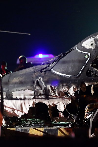 Rescuers stand next to the wreckage of a Westwind aircraft after it caught on fire during takeoff at Manila international airport in Manila