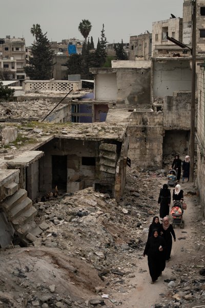 In this Thursday, March 12, 2020 photo, women walk in a neighborhood heavily damaged by airstrikes in Idlib, Syria.