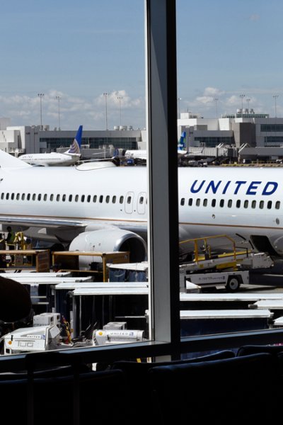 In this file photo, a passenger waiting for her flight to board stands in the airport terminal as a United Airlines plane is loaded at a gate at Denver International Airport in Denver, Colorado.