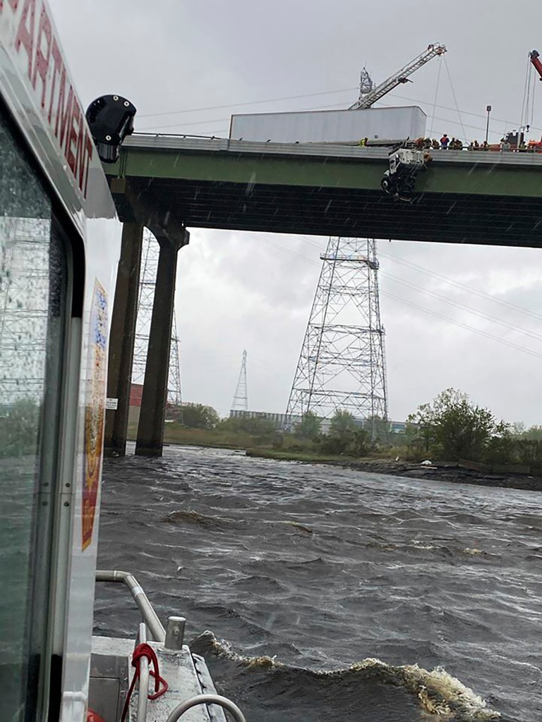In this Monday, April 13, 2020, photo provided by the Chesapeake Fire Department, Chesapeake firefighters try to rescue the driver of a tractor trailer on the High Rise Bridge over the Elizabeth River, in Chesapeake, Va.