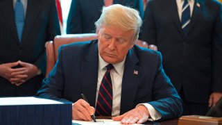 Donald Trump signs the CARES Act in the Oval Office