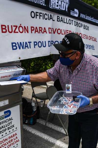 In this Aug. 18, 2020, file photo, poll workers help a voter put their mail-in ballot in an official Miami-Dade County drive- thru ballot drop box during Florida Primary Election amid the coronavirus pandemic, in Miami, Florida.