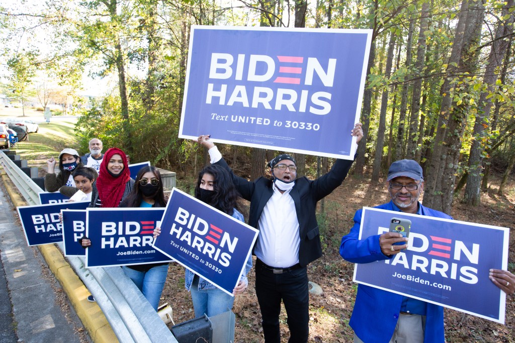Gwinnett county voters including Menar Hague (C) wave Biden-Harris campaign signs at the entrance to Lucky Shoals Park polling station on November 3, 2020 in Norcross, Georgia.   