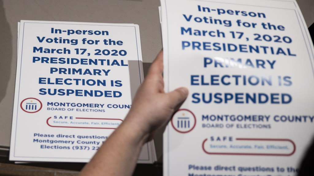 County election workers hand out election delayed signs to put up at polling stations in Dayton, Ohio on March 17, 2020 after the primaries were canceled due to the coronavirus.