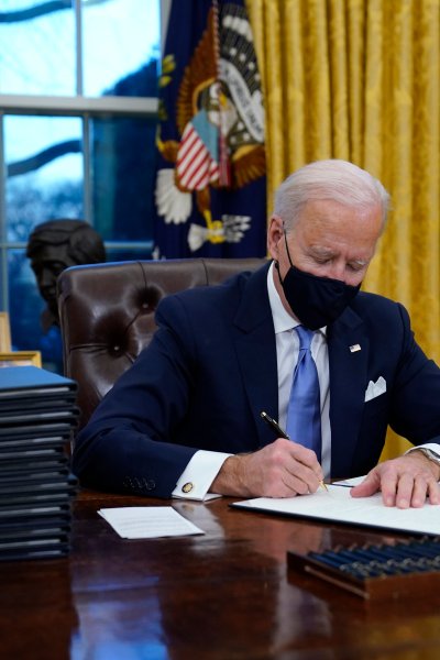 President Joe Biden signs his first executive order in the Oval Office of the White House on Wednesday, Jan. 20, 2021, in Washington. 