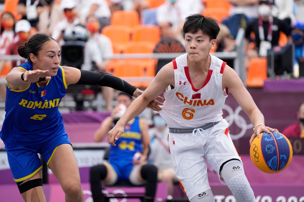 Chinas Yang Shu, rechts, geht während des 3. Basketballspiels der Frauen bei den Olympischen Sommerspielen 2020 am Samstag, 24. Juli 2021, in Tokio, Japan, an der Rumänin Sonia Orso vorbei.