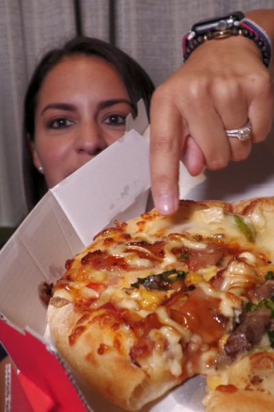 A woman points to a pizza.
