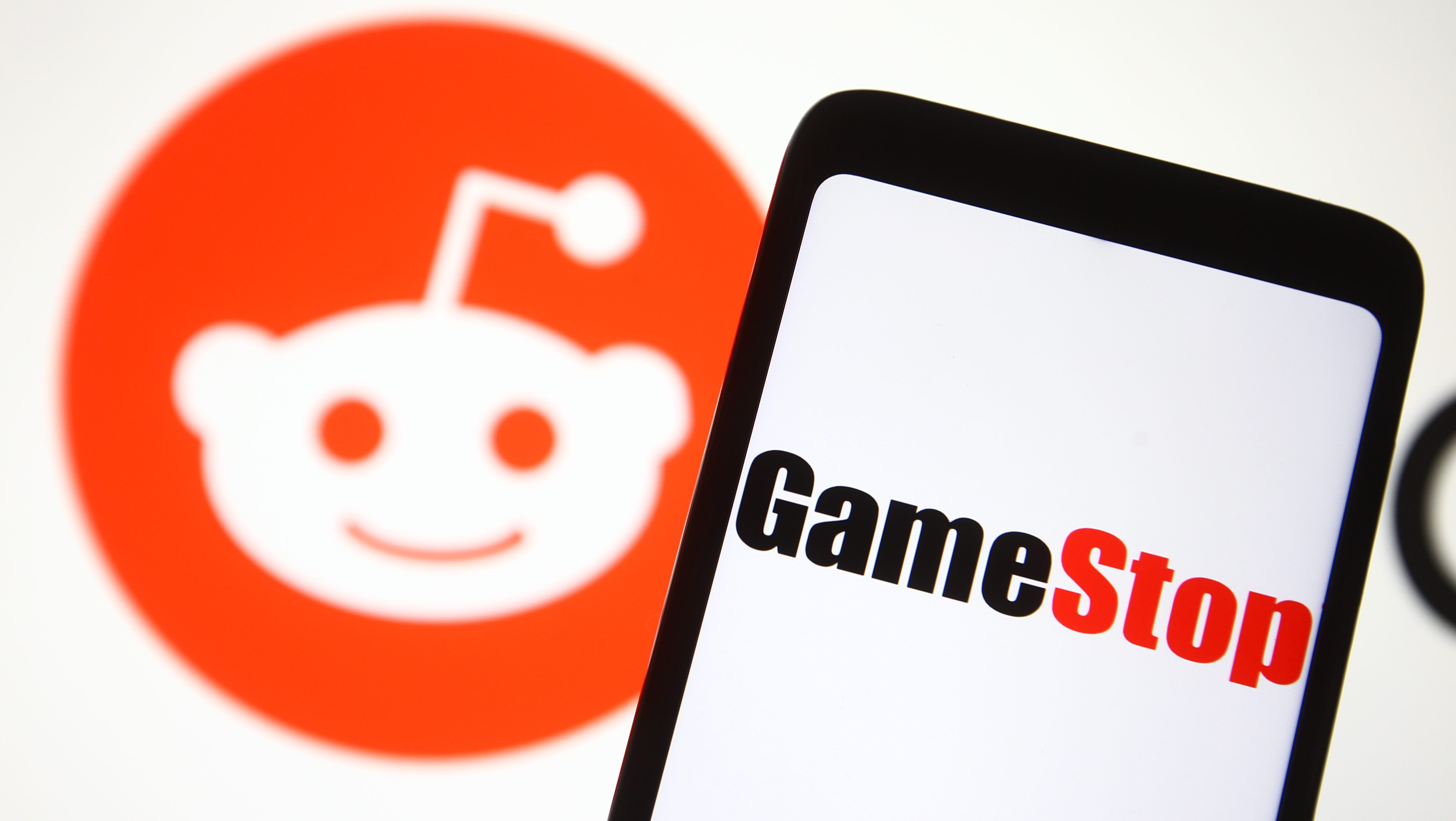 A GameStop logo seen in front of Reddit logo. A Reddit community turned Wall Street upside down in January when users of r/WallStreetBets created a short squeeze with the gaming retailer's stocks.