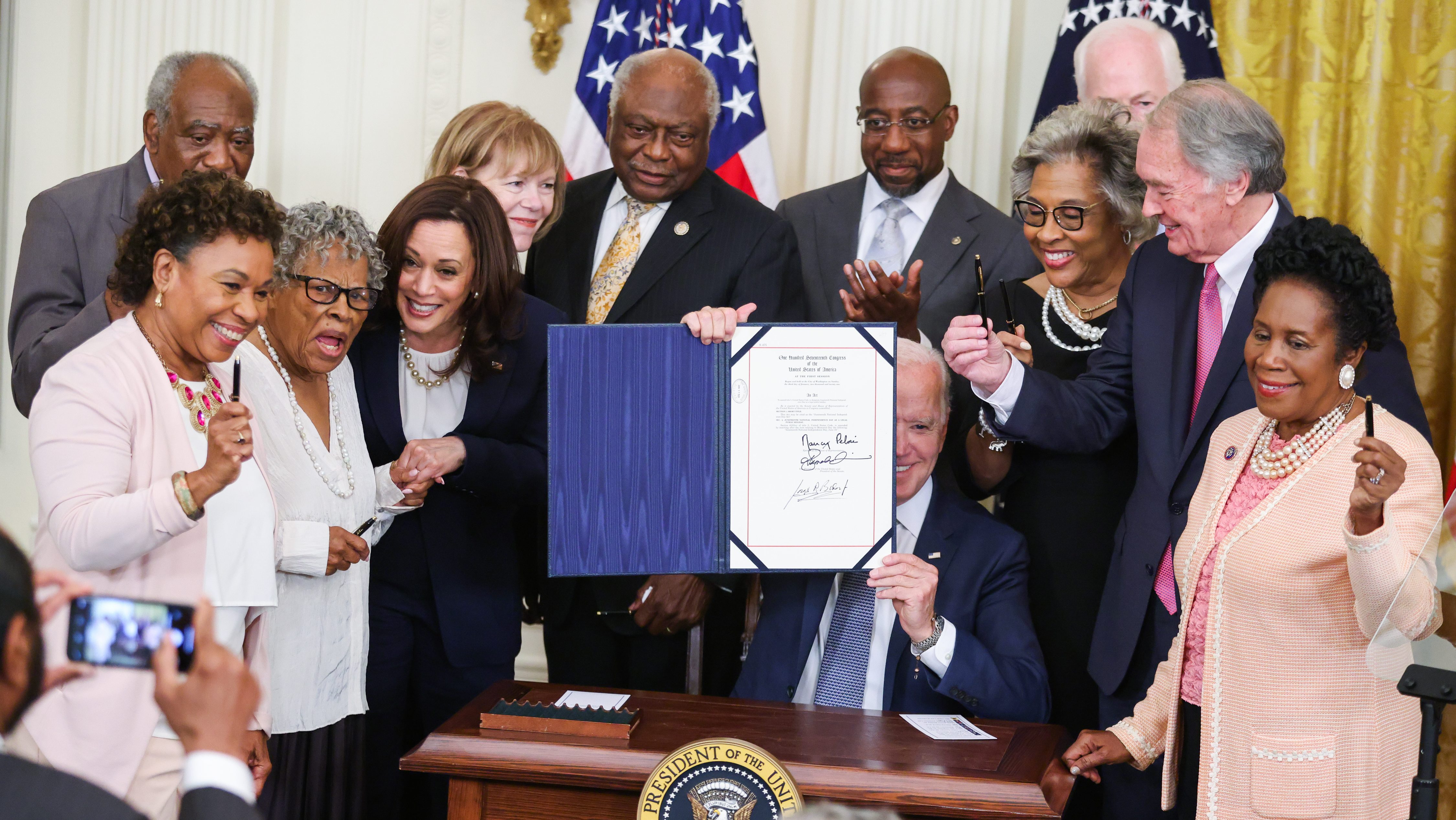 President Joe Biden holds up a signed Juneteenth National Independence Day Act during a ceremony in the East Room of the White House in Washington, D.C., U.S., on Thursday, June 17, 2021. Biden signed the legislation that will make June 19 a federal holiday commemorating the end of slavery in the United States after the House and Senate passed the bill in votes earlier this week.