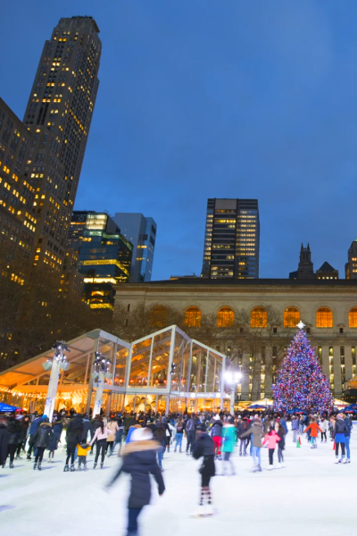 Ice skaters at night in New York City with Christmas Tree in background.