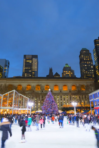 Ice skaters at night in New York City with Christmas Tree in background.