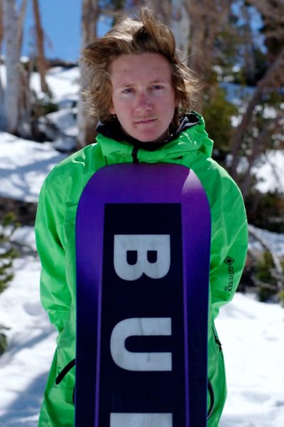 Red Gerard stands in snow wearing green and purple uniform.