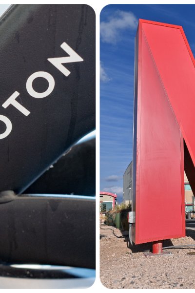 peloton logo and name on a Peloton bicycle; Netflix N logo sitting outdoors