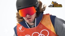 A man wearing a helmet, goggles and ski gear with snow in the background