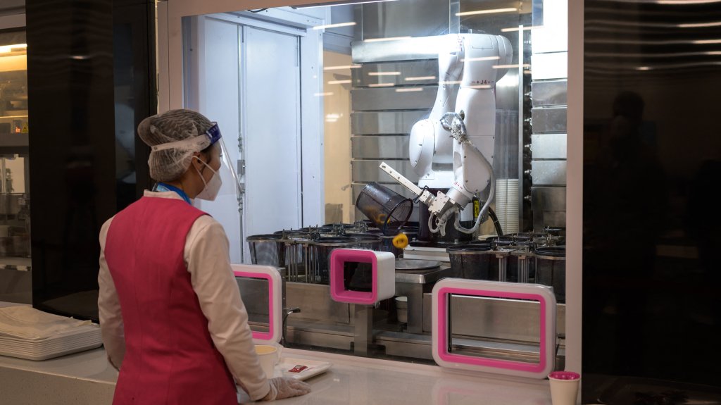 A worker waits for a robot processing an order at the dining hall of the Main Press Center ahead of the 2022 Winter Olympics in Beijing, on January 28, 2022.