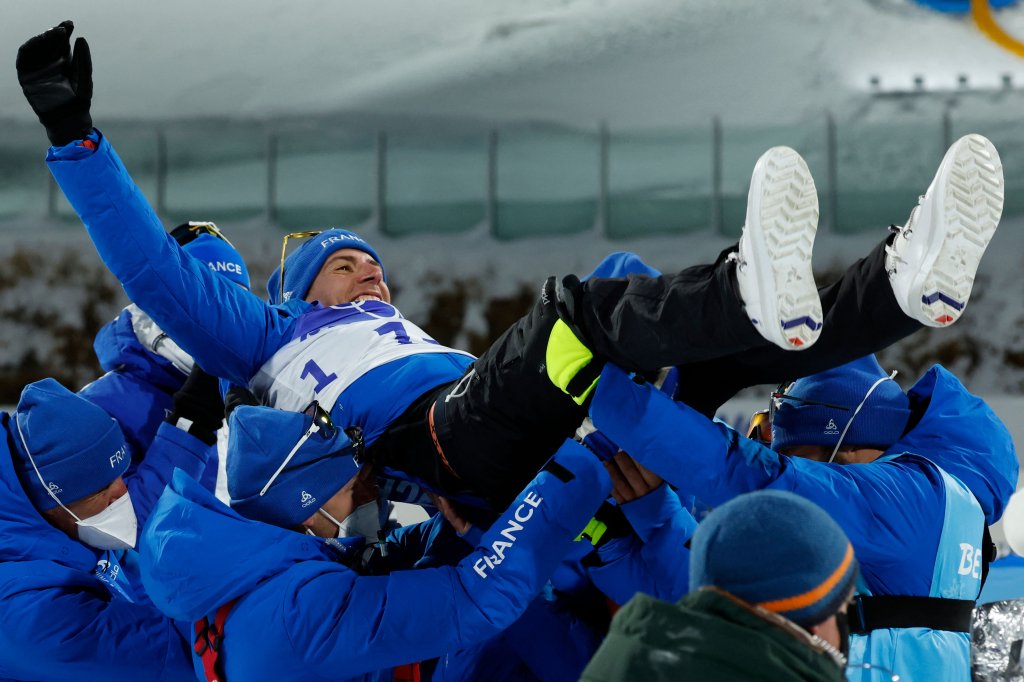Team members toss gold medallist Quentin Fillon Maillet of Team France as they celebrate on the podium