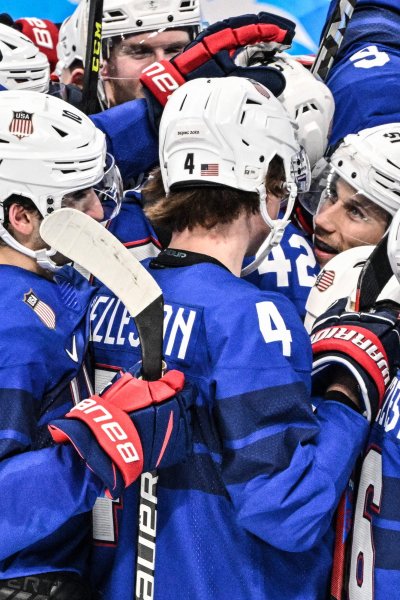 USA's Andy Miele (C-R) and USA's players celebrate victory after the men's preliminary round group A match of the Beijing 2022 Winter Olympic Games ice hockey competition between USA and Germany,