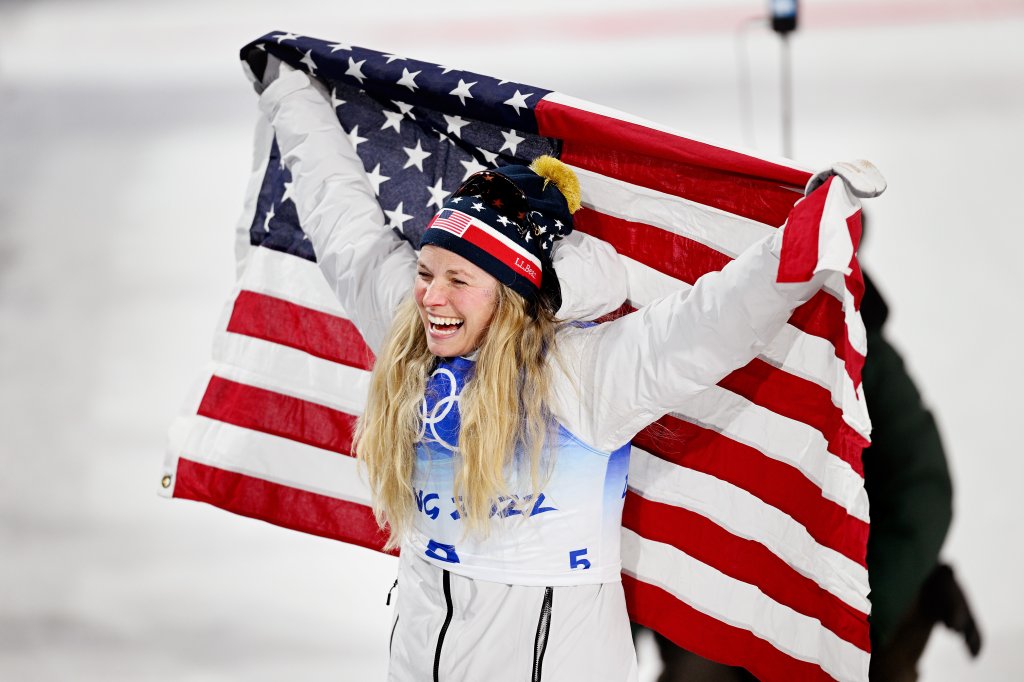 Bronze medallist, Jessie Diggins of Team USA celebrates with a flag during the Women's Cross-Country Sprint Free Final flower ceremony