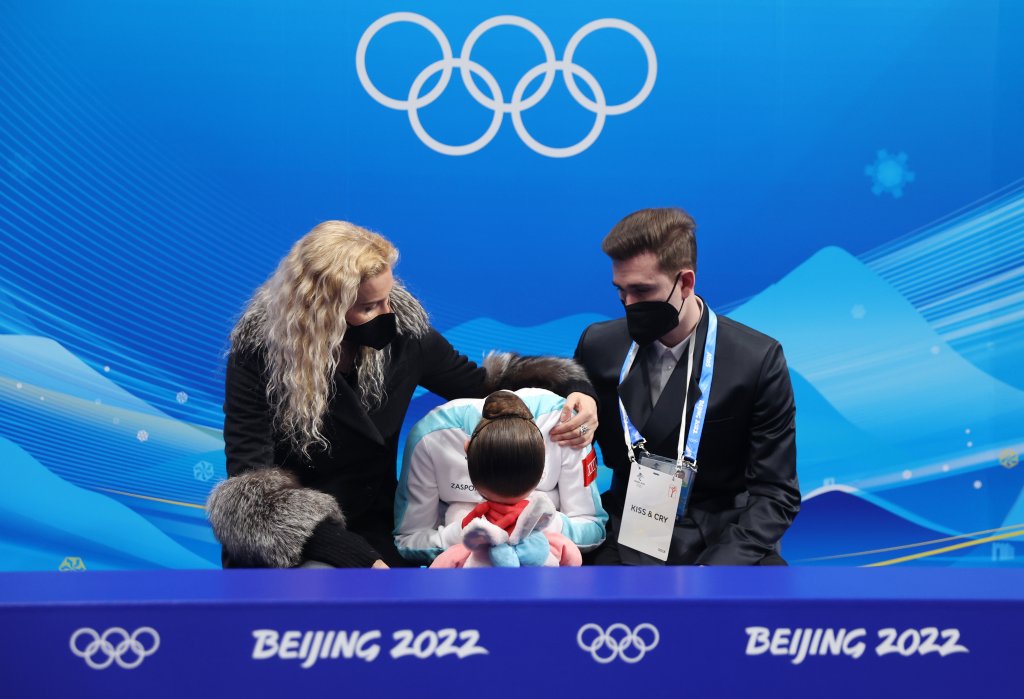 Kamila Valieva of Team ROC reacts to her score with choreographer Daniil Gleikhengau, right, and coach Eteri Tutberidze, left, after the Women's Free Skate event at the 2022 Winter Olympic Games, Feb. 17, 2022, in Beijing.