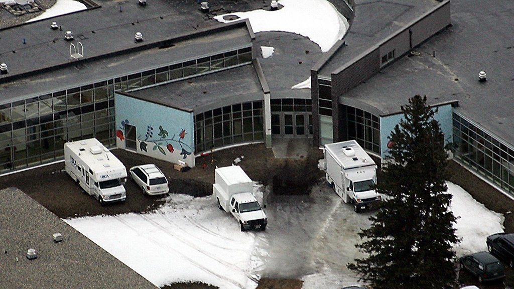 Police and investigators' vehicles are parked in front of the Red Lake Senior High School