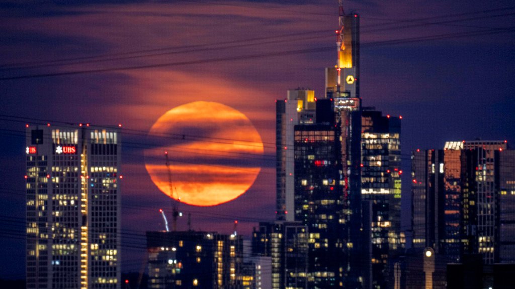 The full moon rises behind buildings in the banking district in Frankfurt, Germany, 
