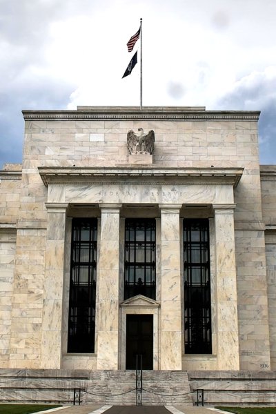 Exterior shot of the Federal Reserve building with dramatic clouds in sky.