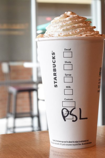 To go Starbucks cup with whipped cream and PSL written in marker.