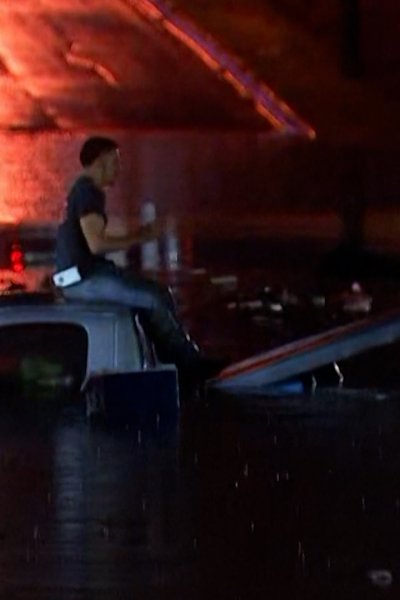Man sits on top of truck stuck on flooded highway at night