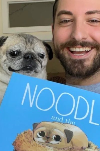 Man holds pug and book with illustrated pug