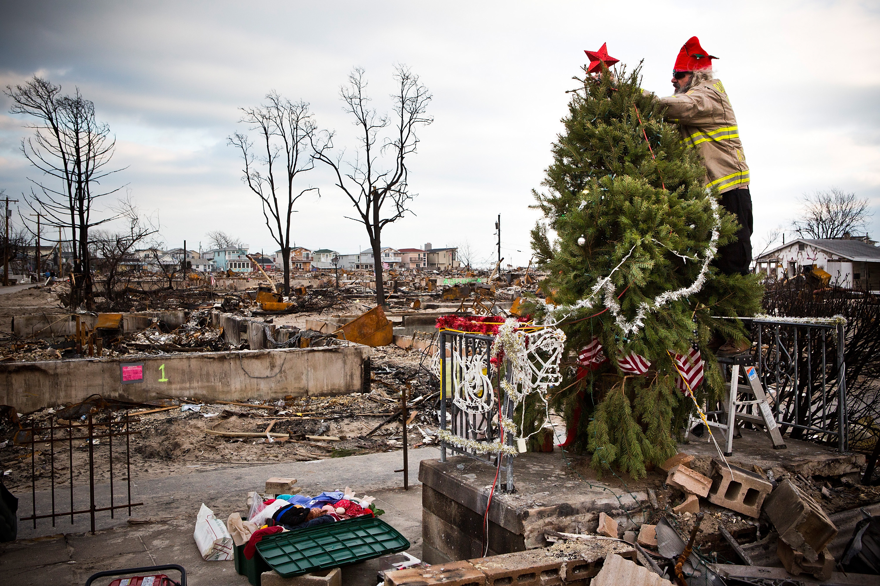Edward "Roaddawg" Manley, a volunteer and honorary firefighter with the Point Breeze Volunteer Fire Department, places a star on top of a Christmas tree Dec. 25, 2012, in the Breezy Point neighborhood of New York City. Residents are still struggling to recover from a massive fire that destroyed over 100 homes during Superstorm Sandy.