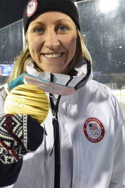 A woman smiling and holding an Olympic gold medal