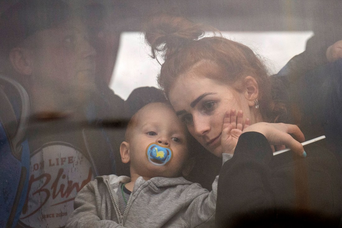 A woman holds her baby inside a bus as they leave Kyiv, Ukraine, Feb. 24, 2022.  (Emilio Morenatti/AP)